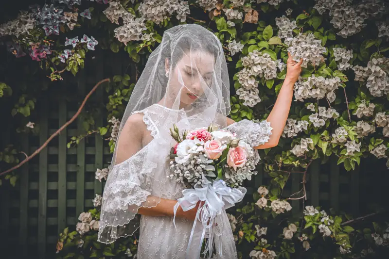 Artistic bridal portrait framed through a veil and flowers.