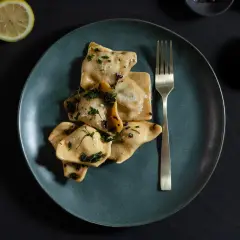 Beef cheek ravioli served on a dark ceramic plate with herbs and butter, captured in a moody studio-style food photography setup in Perth.