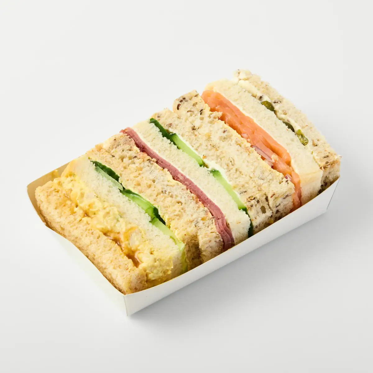 Tray of assorted filled finger sandwiches photographed on a clean white background