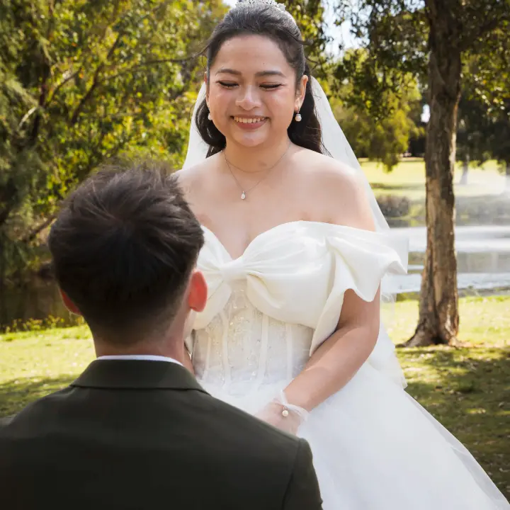 Bride smiling down at the groom during a playful lakeside wedding portrait.