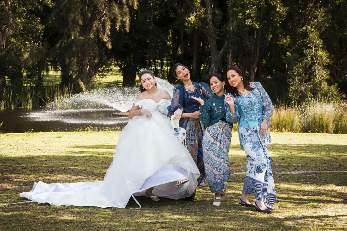 Bride with bridesmaids posing beside a fountain during post-ceremony portraits