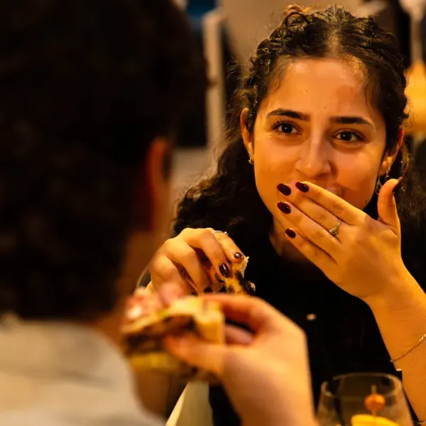 Candid portrait of a woman eating pizza, authentic lifestyle photography for restaurant branding and web design.