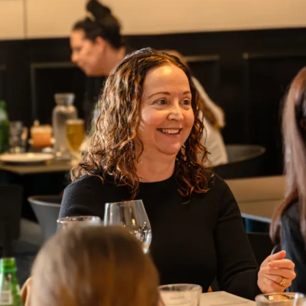 Candid shot of a woman smiling at a dinner event, capturing the atmosphere for Perth hospitality website design.