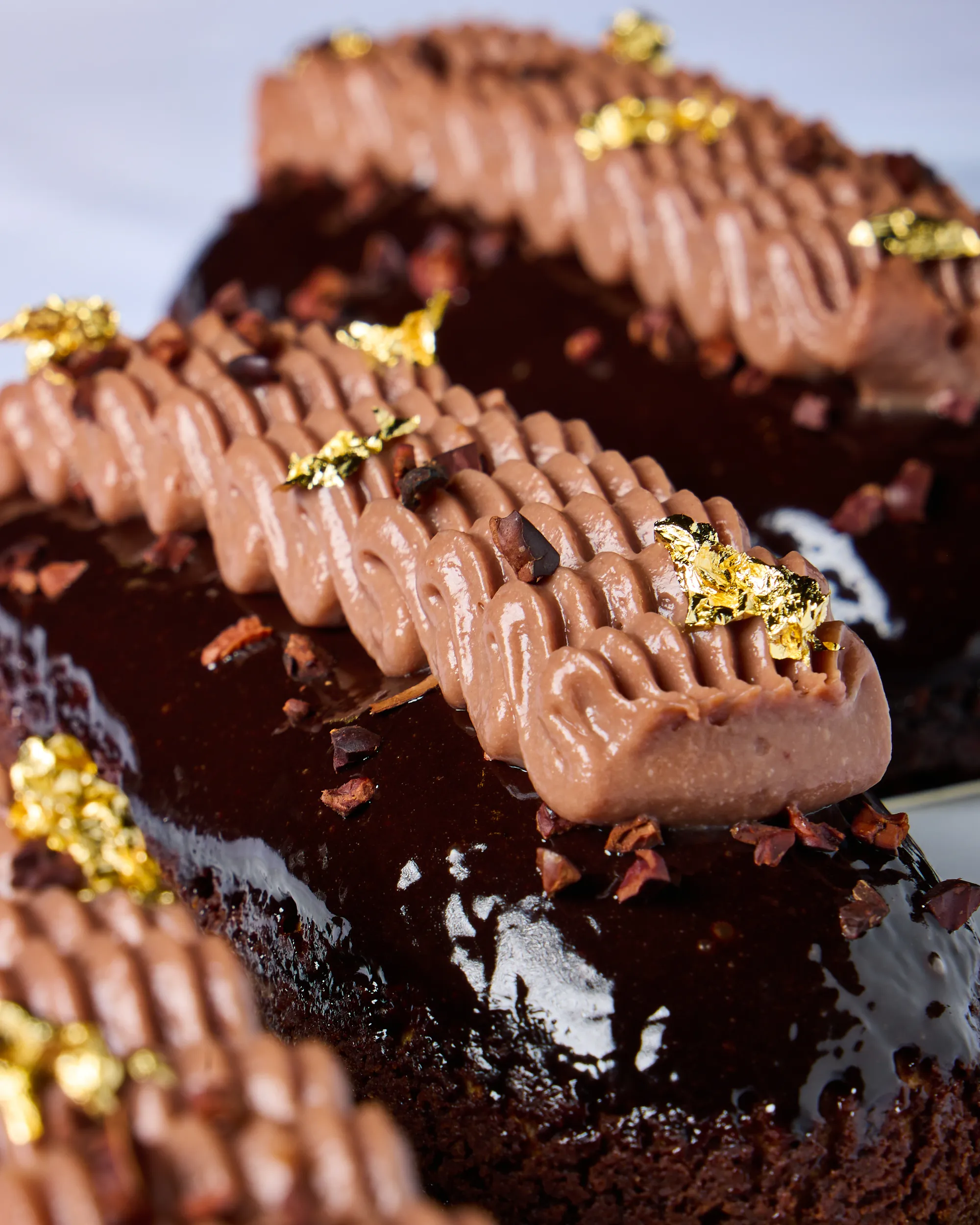 Glossy chocolate dessert cake finished with gold leaf