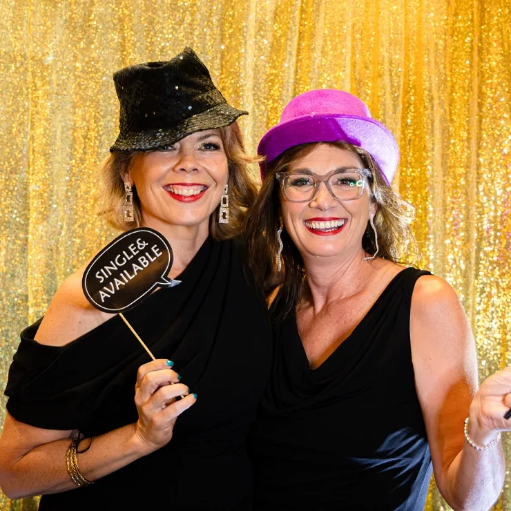 Guests posing in a gold-backdrop photo booth, capturing fun social moments for Perth corporate event marketing.