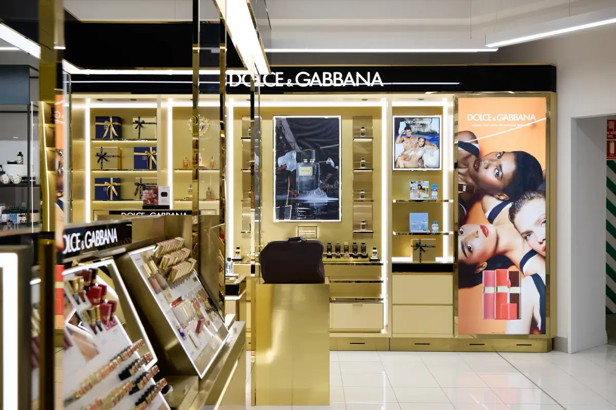 Dolce&Gabbana Beauty back wall at Myer Perth with polished gold shelving, backlit campaign panels, fragrance bottles and navy gift boxes
