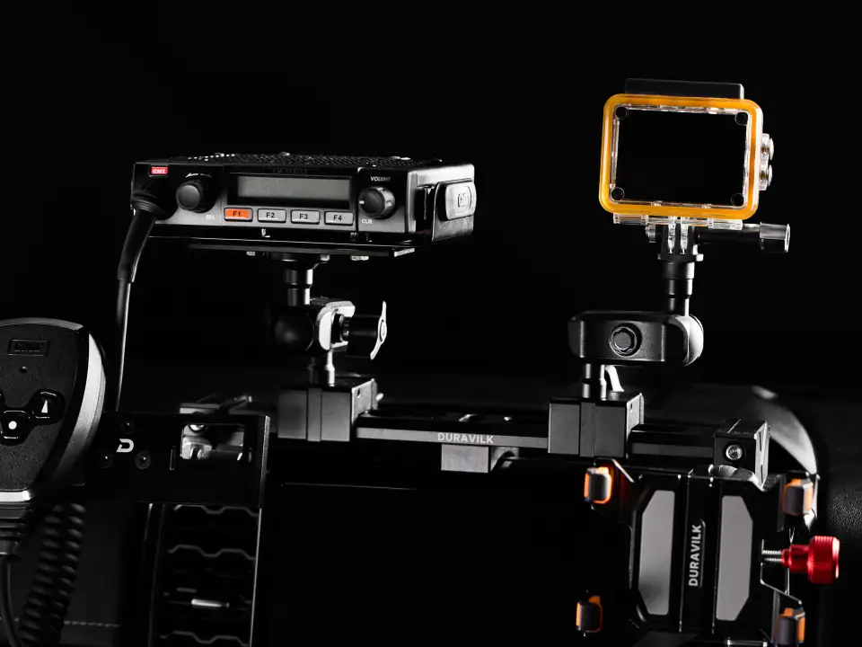 Duravilk dashboard mounting rail holding a radio and an action camera, with a branded device holder and red adjustment knob in the foreground