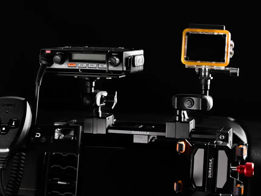 Duravilk dashboard mounting rail holding a radio and an action camera, with a branded device holder and red adjustment knob in the foreground