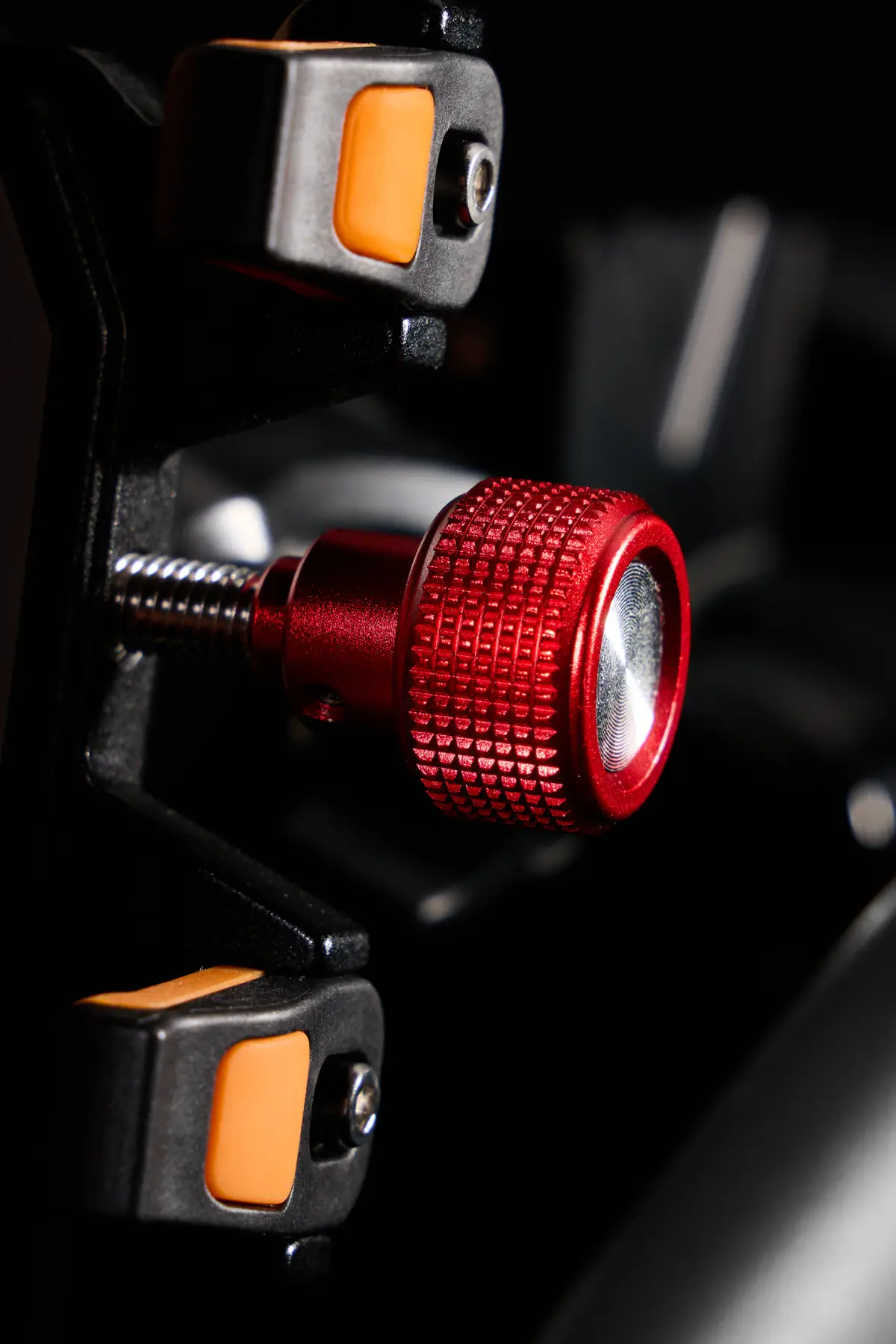 Close-up of a red knurled adjustment knob and orange contact pads on a black Duravilk device holder