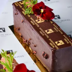 Branded chocolate patisserie slice with raspberries, gold detail, and Duxton Hotel Perth logo wrap.