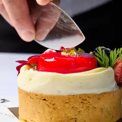 Chef placing gold garnish onto a glossy red cheesecake dessert at Duxton Hotel Perth.