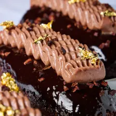 Chocolate eclair topped with piped cream and gold leaf photographed as a premium Duxton Hotel Perth dessert.