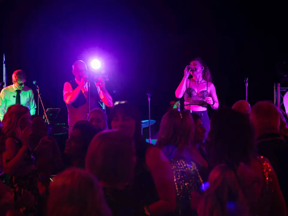 Live band performing on stage with purple lighting while guests watch during a festive event at Duxton Hotel Perth Grand Ballroom