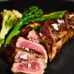 Seared lamb rack sliced medium rare with green garnish and glossy jus photographed for Duxton Hotel Perth fine dining.