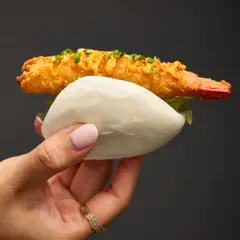 Tempura prawn bao held by hand with crisp coating and soft steamed bun, photographed for Duxton Hotel Perth dining content.