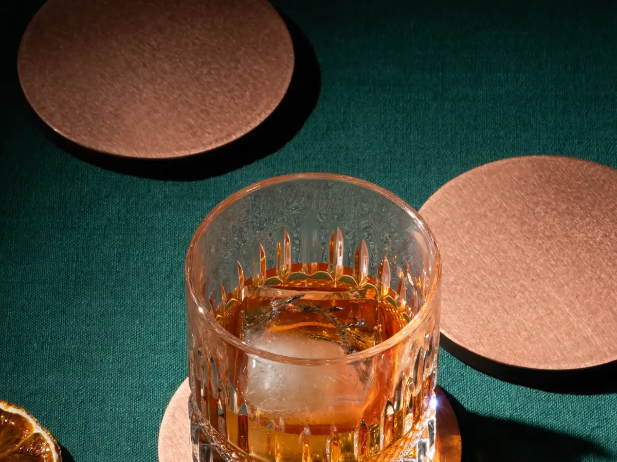 Stack of handcrafted copper coasters showing edge thickness and brushed surface finish