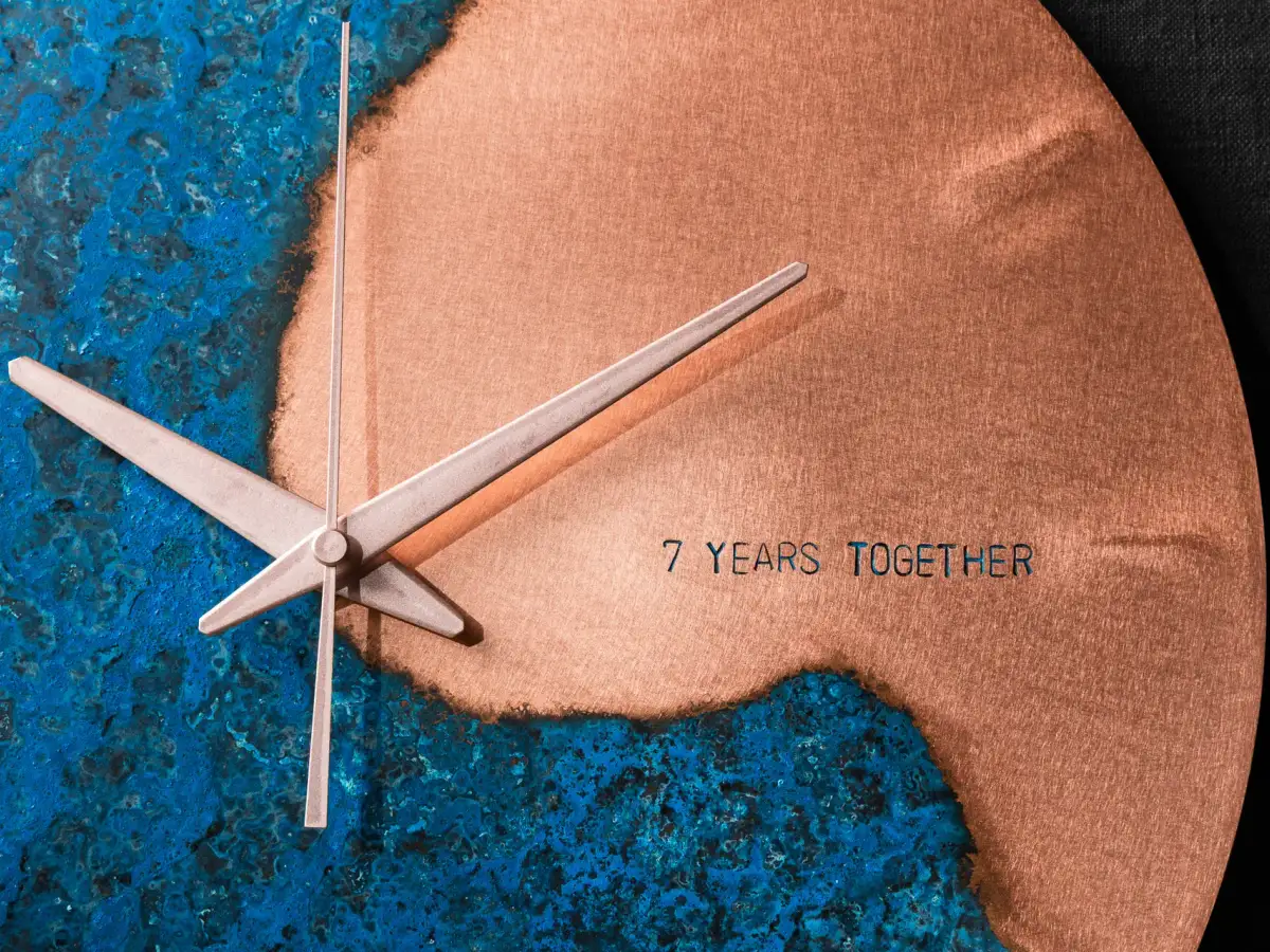 Close-up of a handcrafted Empire Copper wall clock showing blue patina and brushed copper finish with engraved text