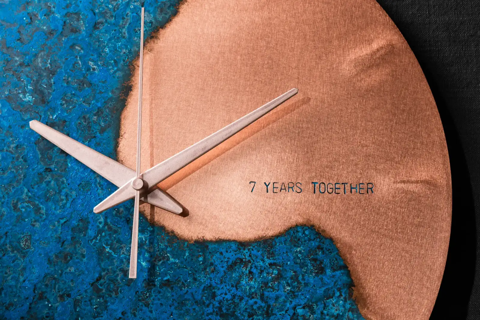 Close-up of a handcrafted Empire Copper wall clock showing blue patina and brushed copper finish with engraved text