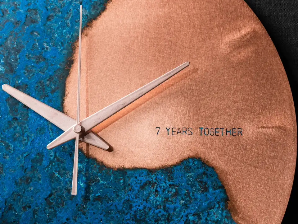 Close-up of a handcrafted Empire Copper wall clock showing blue patina and brushed copper finish with engraved text