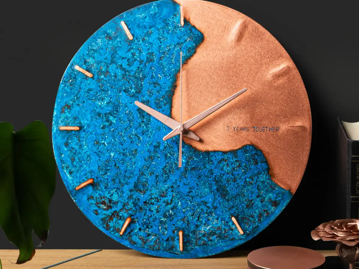 Empire Copper patina wall clock displayed on a wooden shelf beside copper coasters and a bronze rose ornament