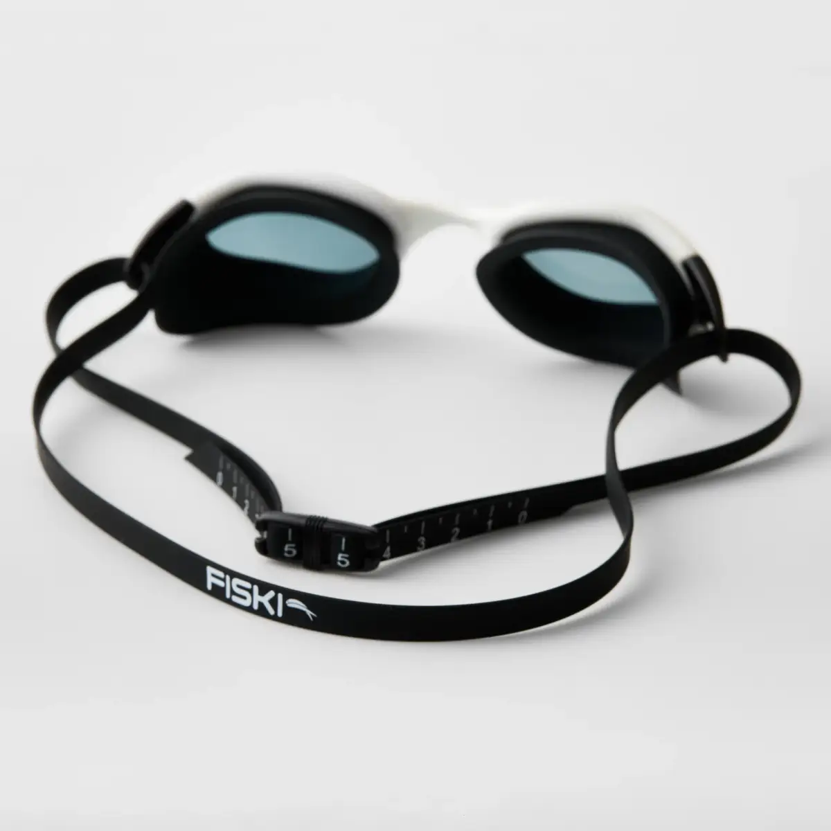 Rear view of black and white Fiski swimming goggles showing the soft silicone eye gaskets, split strap and numbered adjustment clips