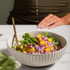 Hand squeezing lime over mango and onion salad, vivid food photography for Perth restaurant social media and website assets.