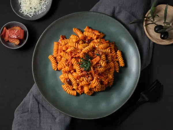 Fusilli pasta with red sauce in moody low lighting, dark and atmospheric bar food photography in Perth.