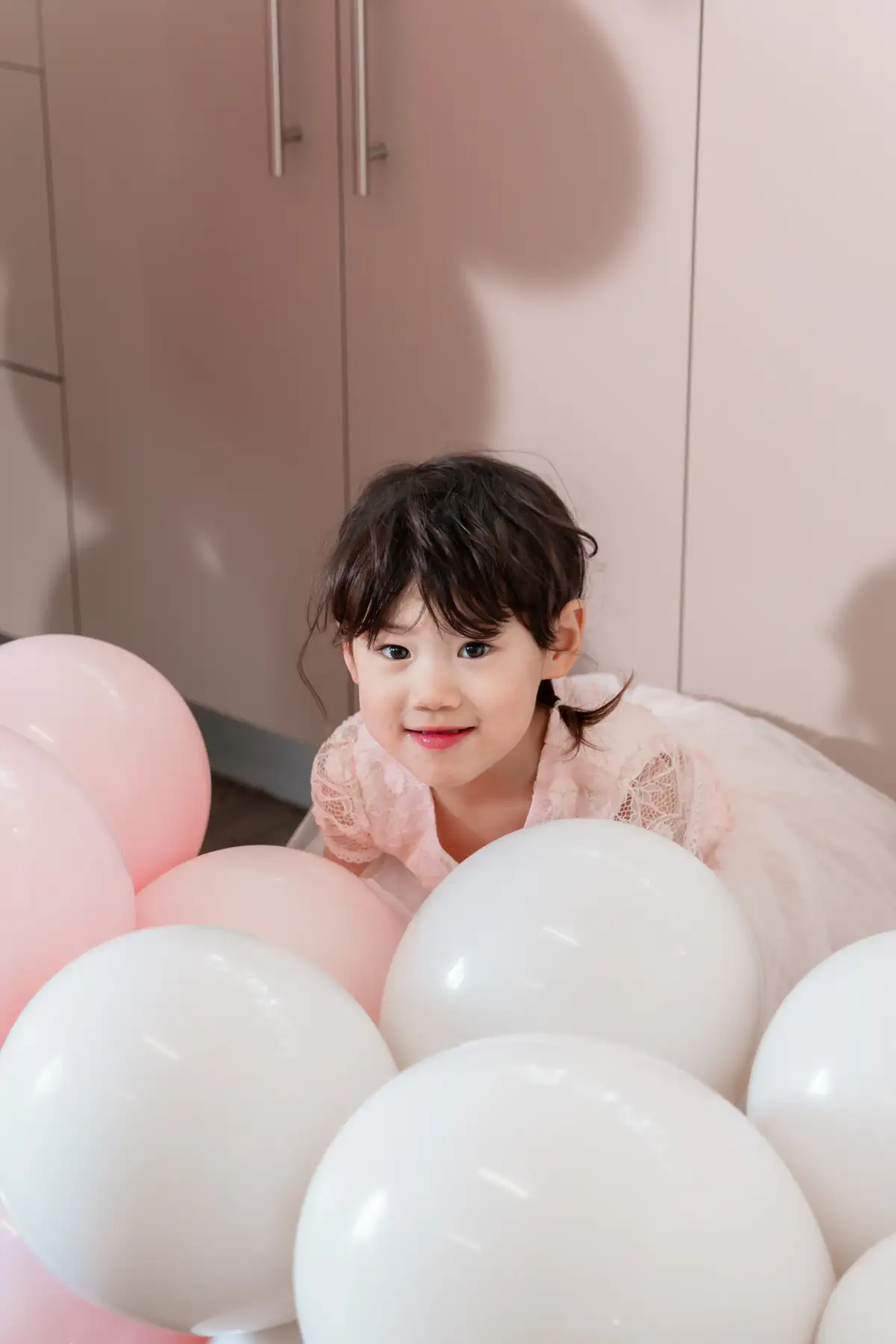 Child playing with pink balloons during a birthday party.
