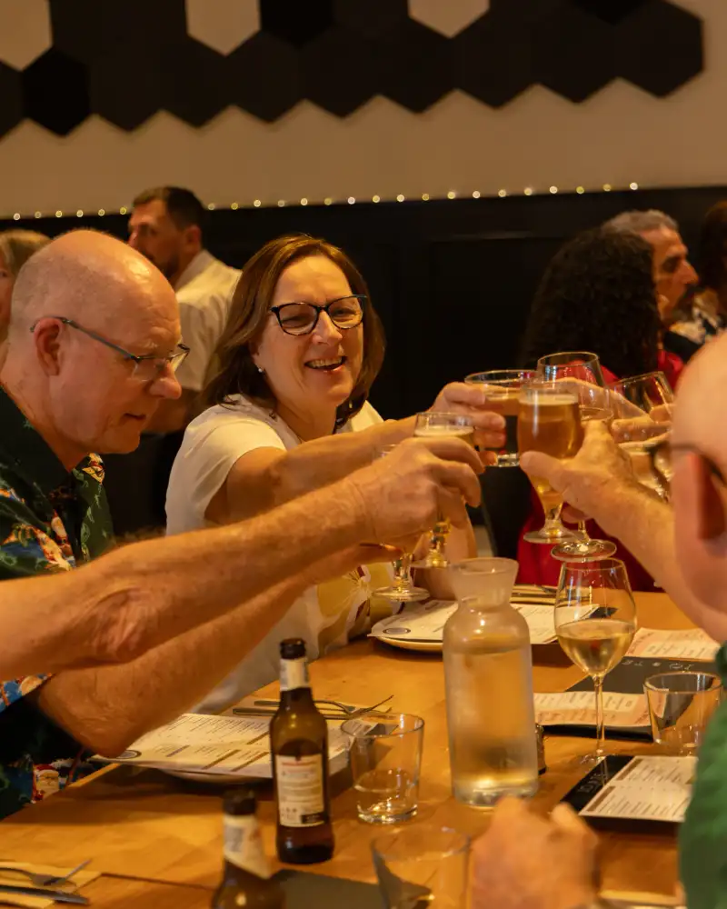 Guests raising glasses in a group toast at a Perth celebration, captured candidly by an event photographer