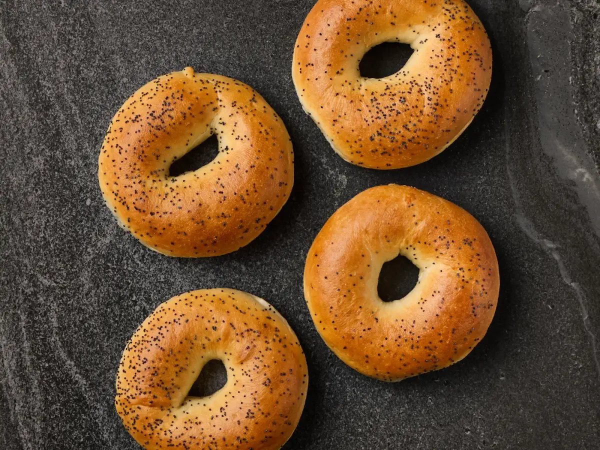 Four Il Granino poppy seed bagels photographed from above on a dark stone surface