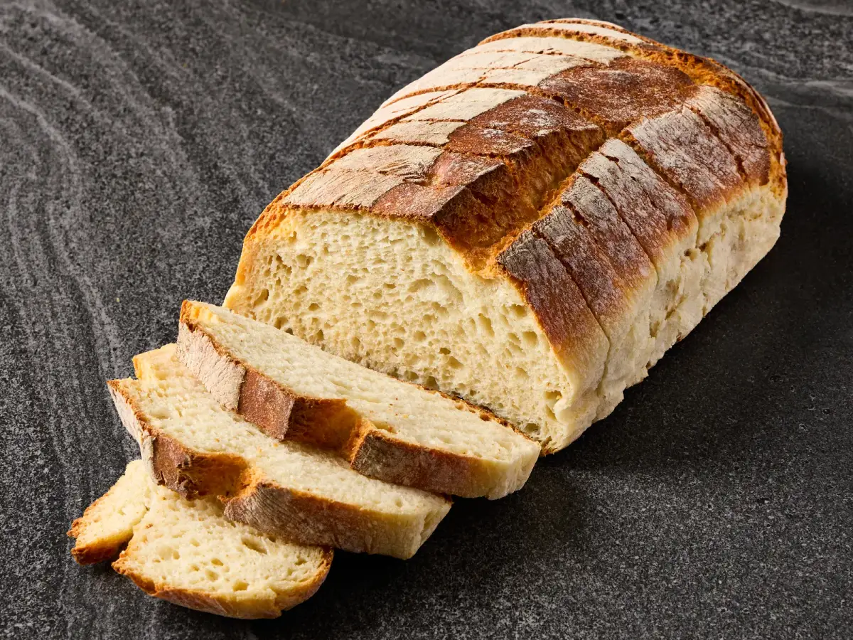 Il Granino artisan sourdough loaf sliced to show the open crumb and floured crust on a dark stone surface