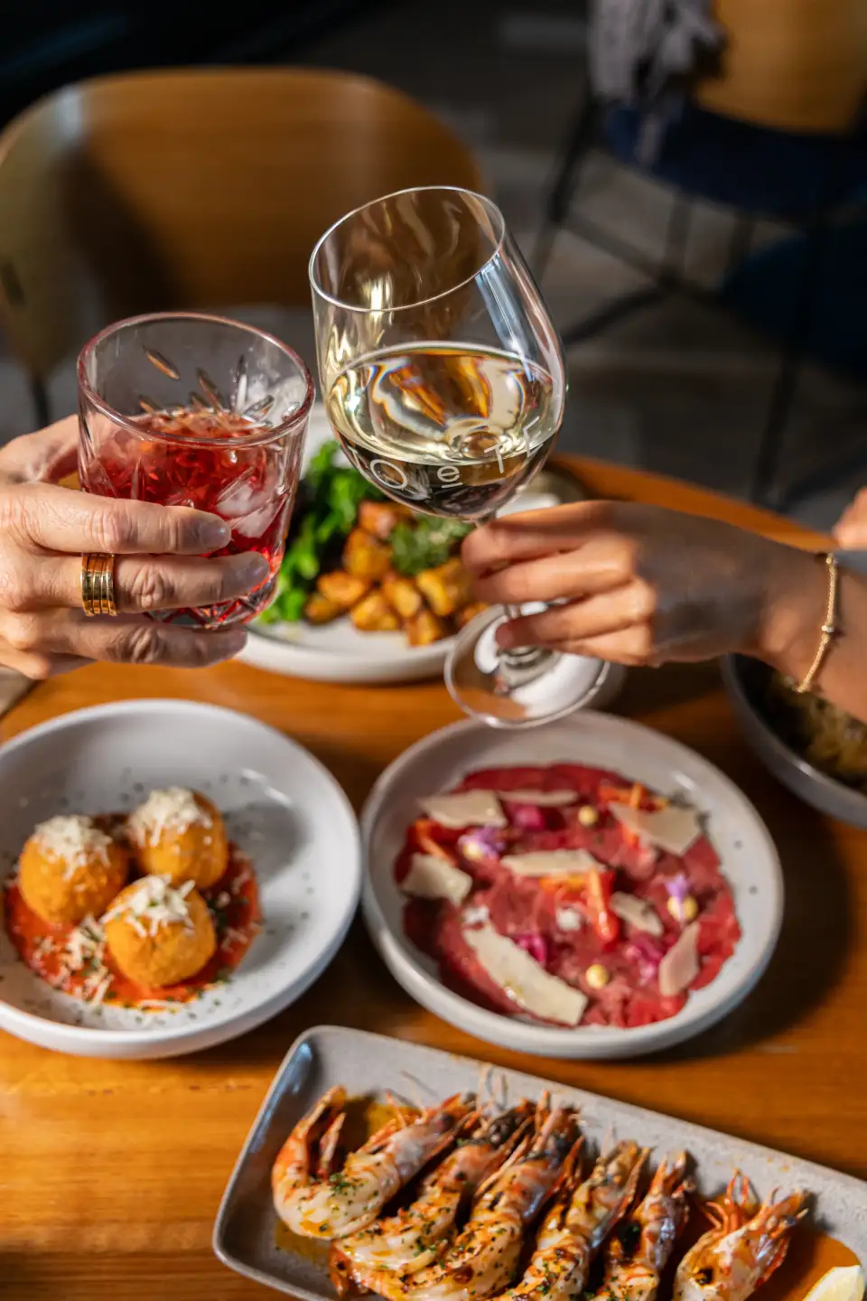 Guests toasting drinks over shared Italian plates at Io e Te Pizzeria e Ristorante in Success Perth