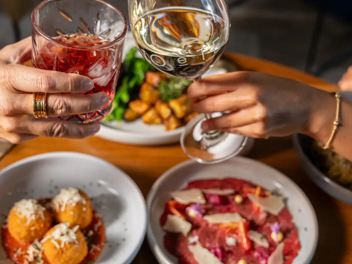 Guests toasting drinks over shared Italian plates at Io e Te Pizzeria e Ristorante in Success Perth