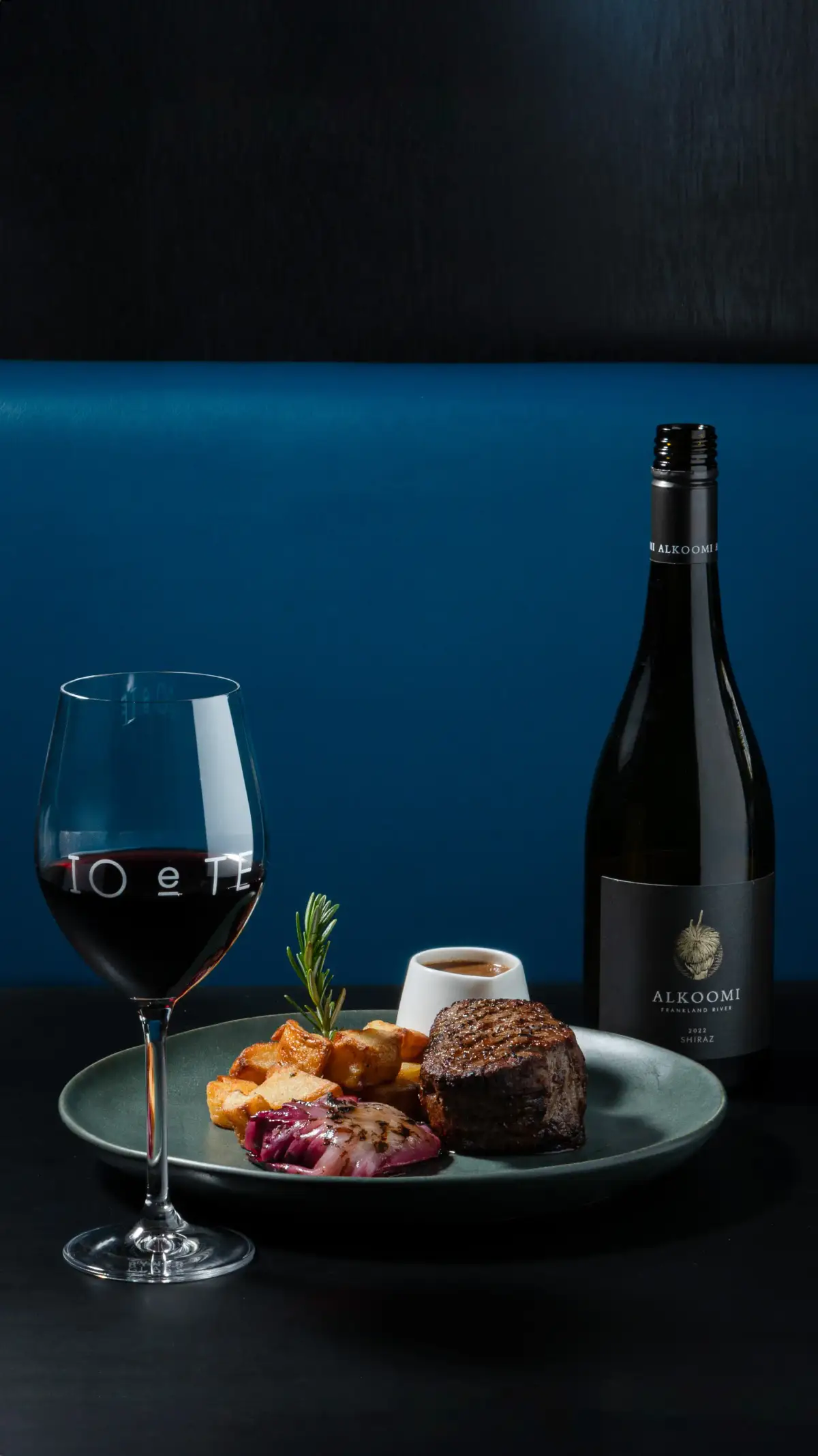 Plated steak with roasted potatoes, red wine, and bottle styling at Io e Te