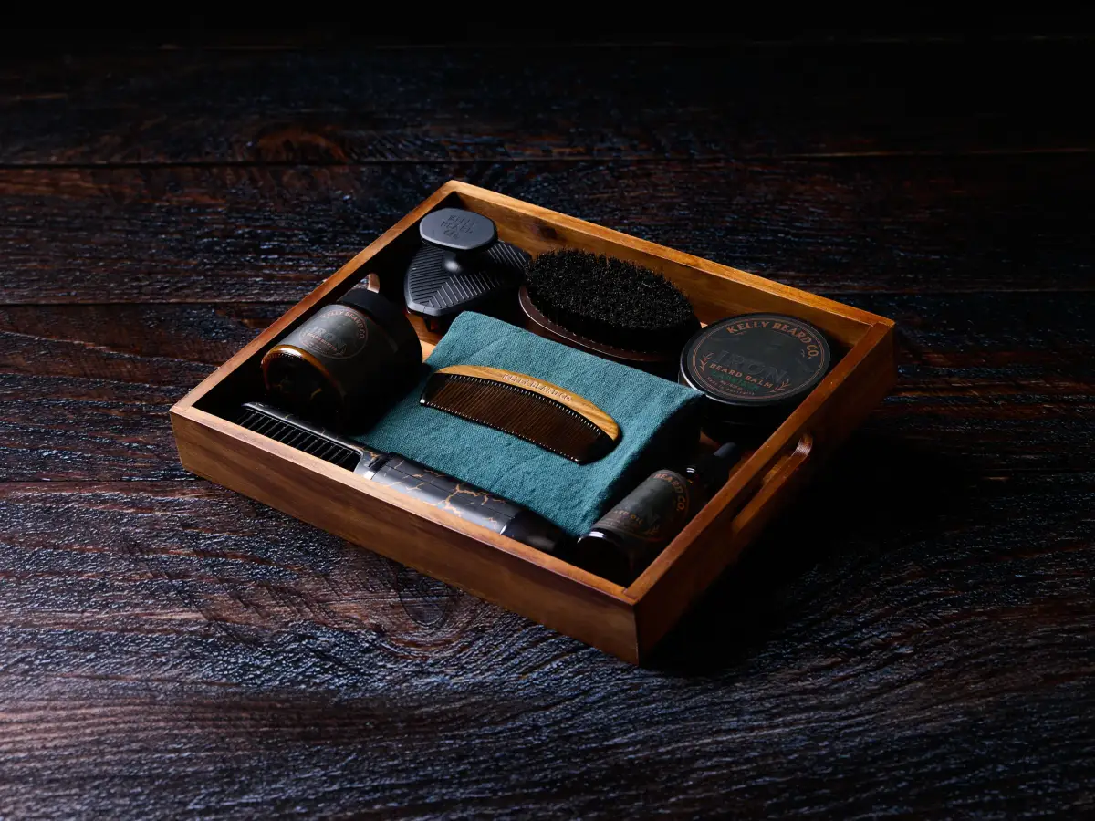 Kelly Beard Co premium beard care kit arranged in a wooden tray with beard balm, beard oil, comb, brush, and grooming tools