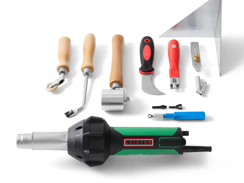 Assorted Kevmor flooring installation tools including rollers, knives, welding accessories, and a Leister heat gun arranged on white