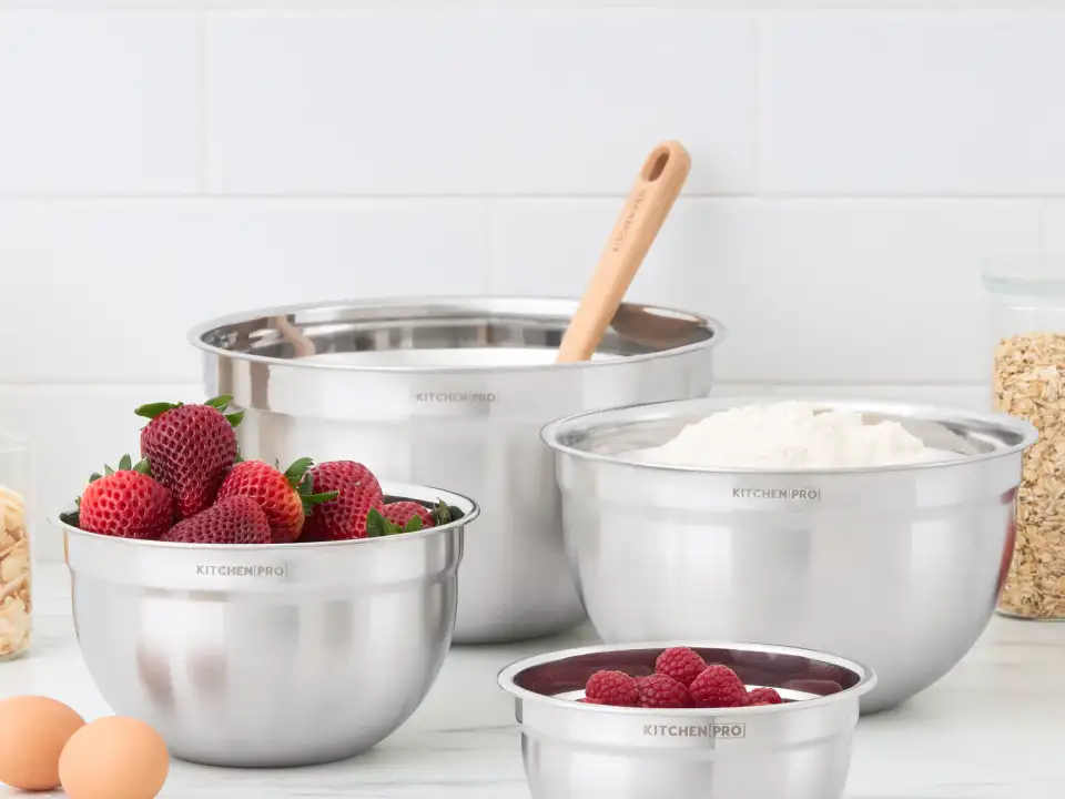 Kitchen Pro stainless-steel mixing bowl set styled with berries, flour, oats, almonds, and eggs in a bright kitchen by Jo-Anne Pabst