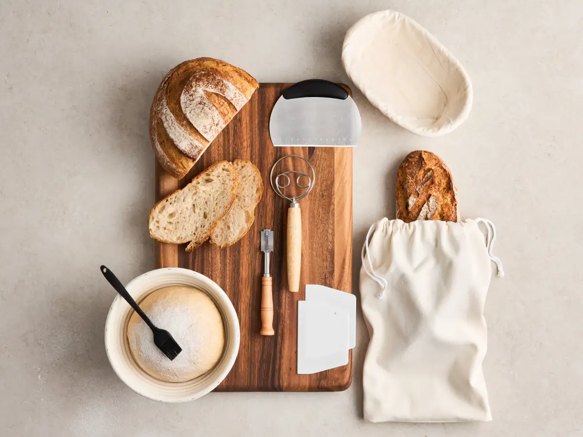 Overhead lifestyle photograph of the Brunswick Bakers bread baking set with bannetons, dough tools, bread board, and artisan loaves