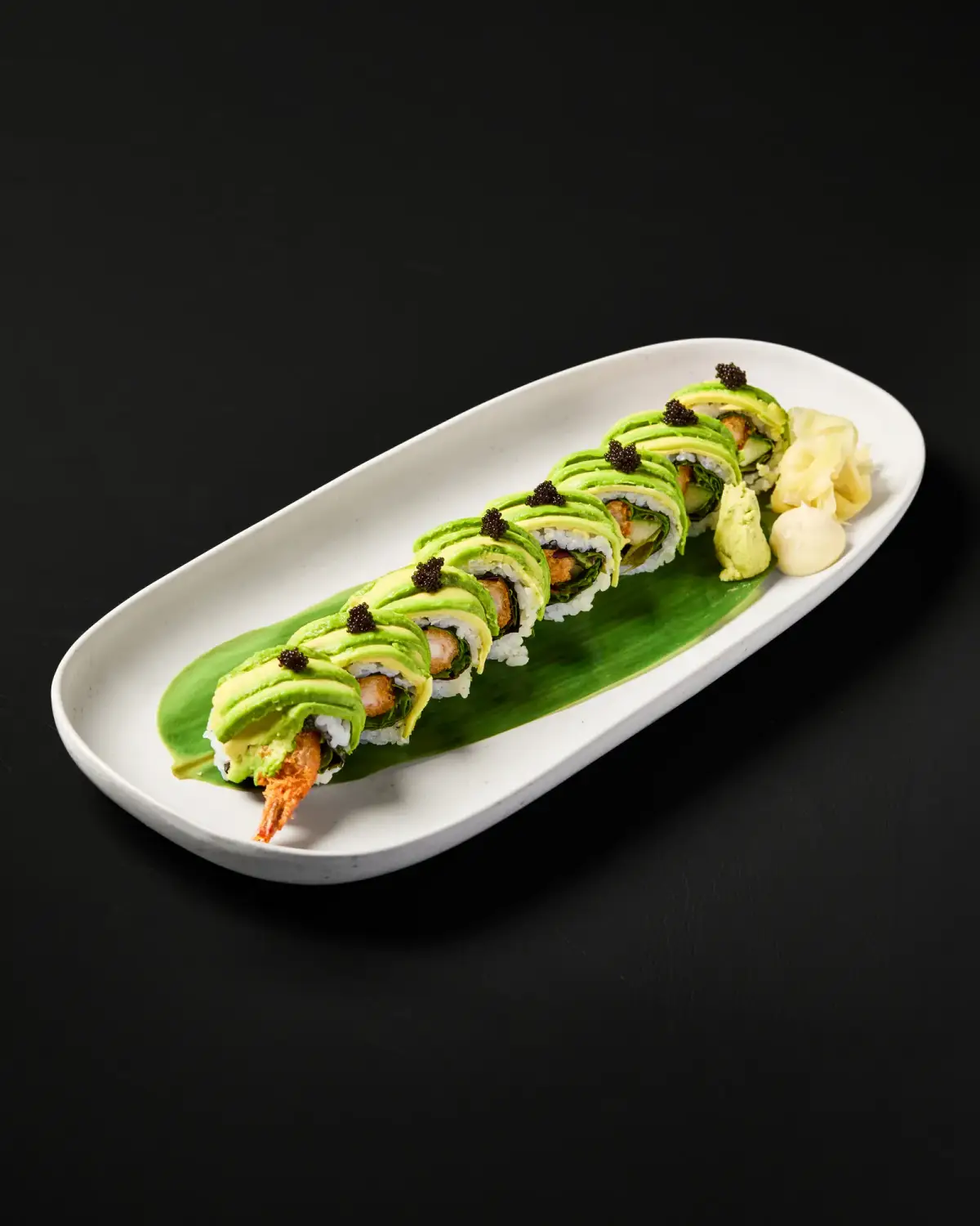 Avocado-topped sushi roll on a long white plate at Kuza Urban Japanese Food.