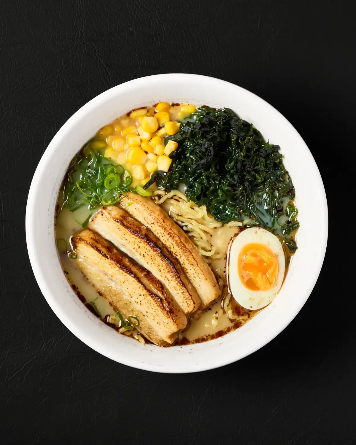 Ramen bowl with sliced meat, egg, corn and seaweed at Kuza Urban Japanese Food.