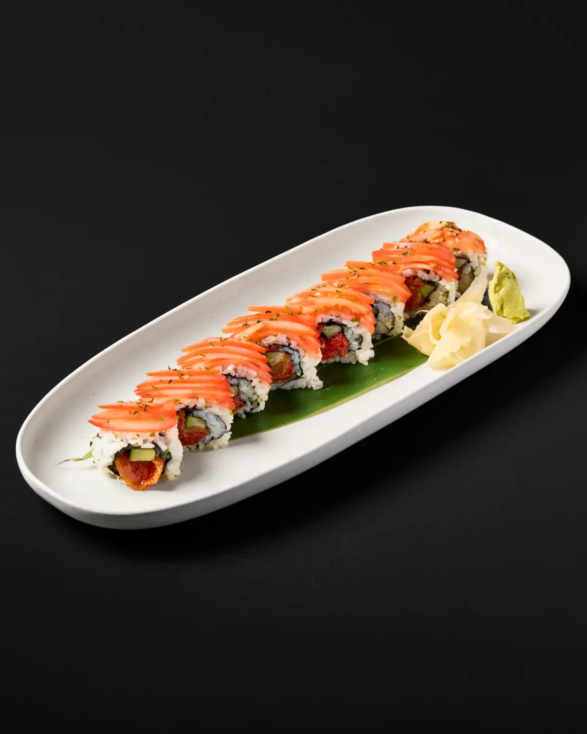 Salmon-topped sushi roll with sauce and lemon at Kuza Urban Japanese Food.
