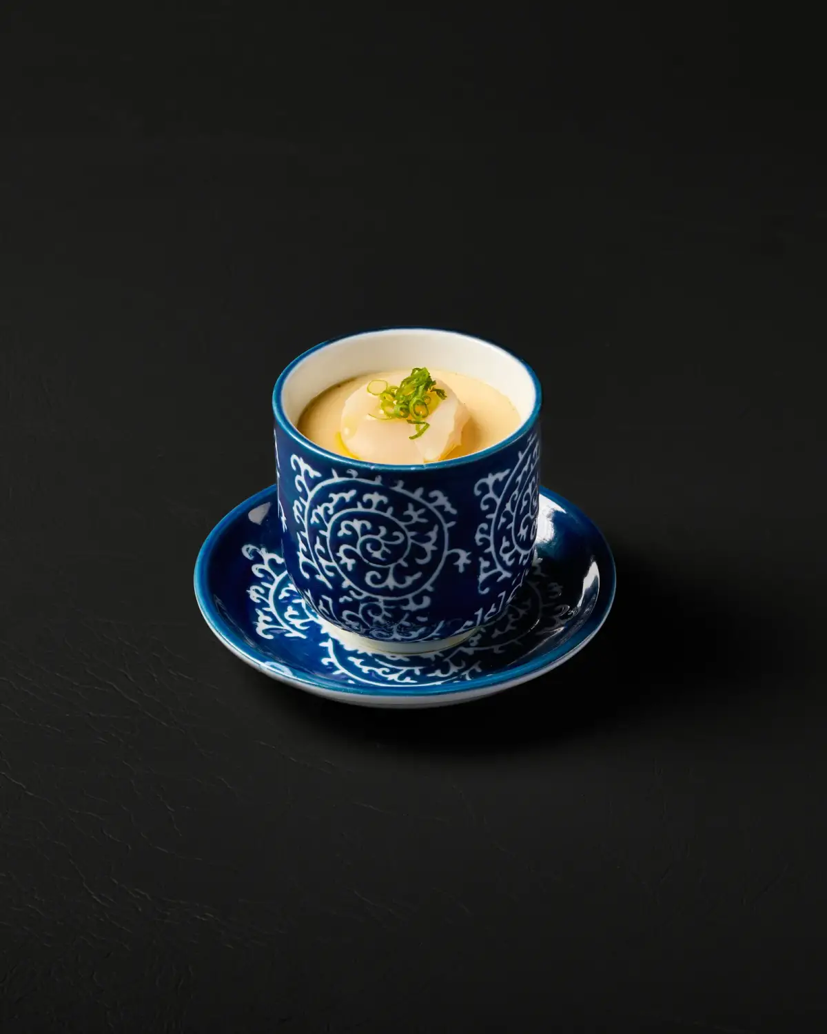 Savoury dish in a blue patterned cup on a matching saucer at Kuza Urban Japanese Food.