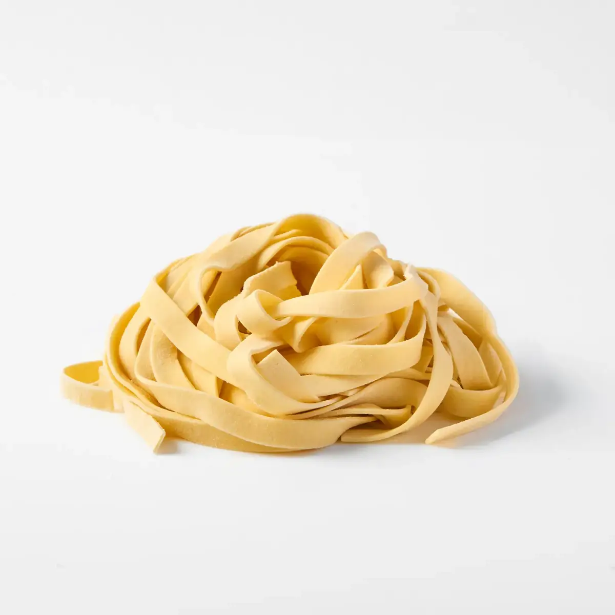 A nest of fresh La Delizia Lab tagliatelle ribbons photographed on a clean white background