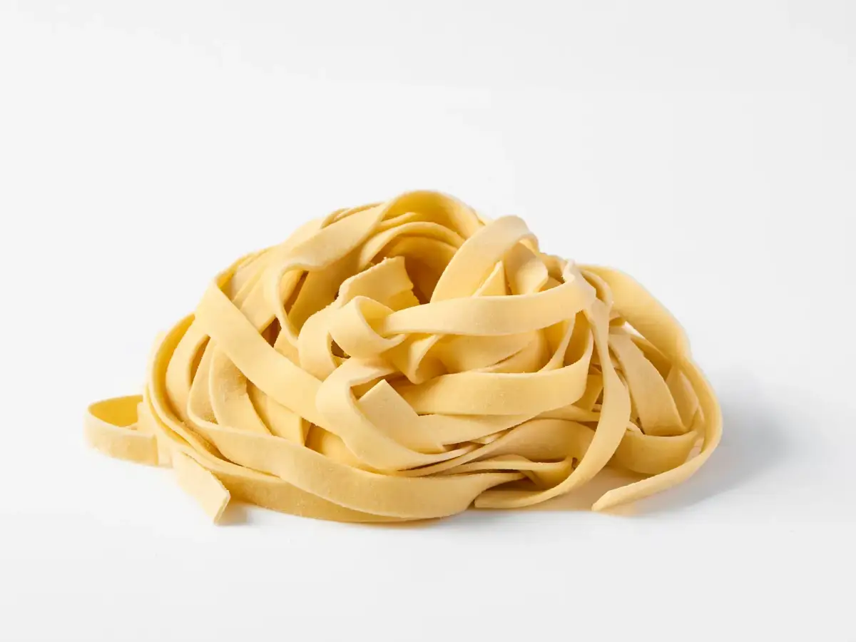 A nest of fresh La Delizia Lab tagliatelle ribbons photographed on a clean white background
