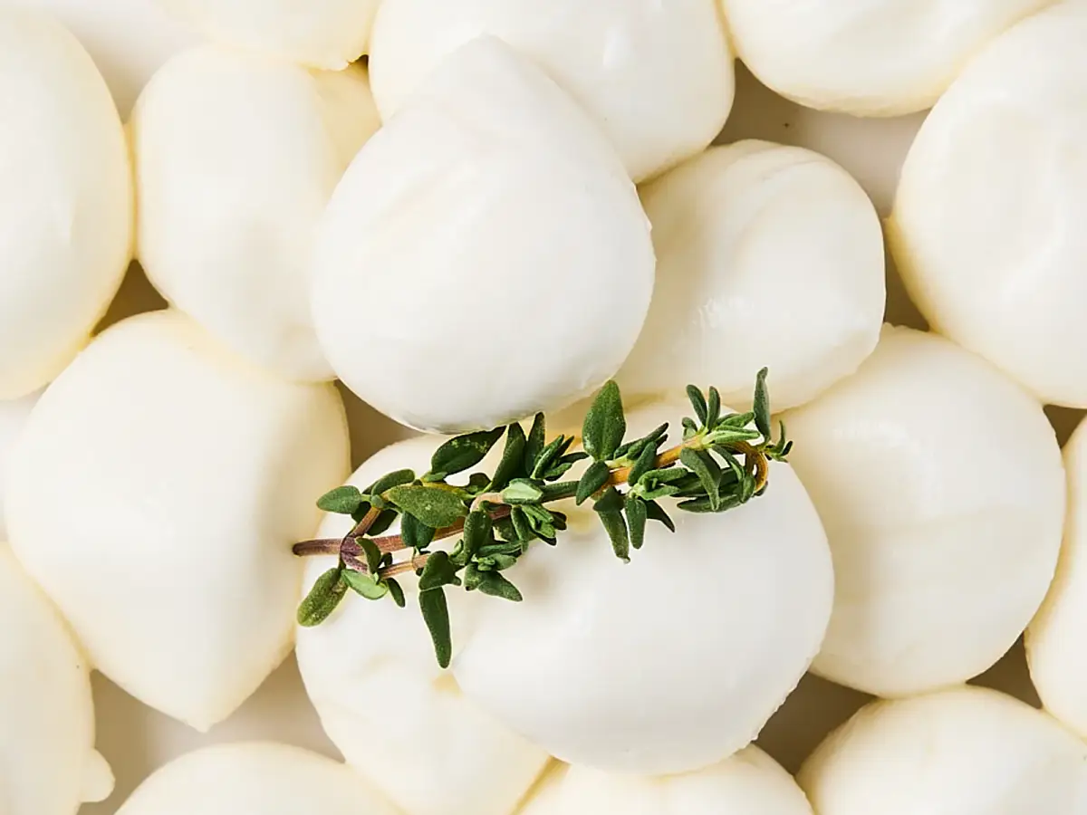 La Delizia Latticini baby bocconcini balls photographed from above with a sprig of fresh thyme