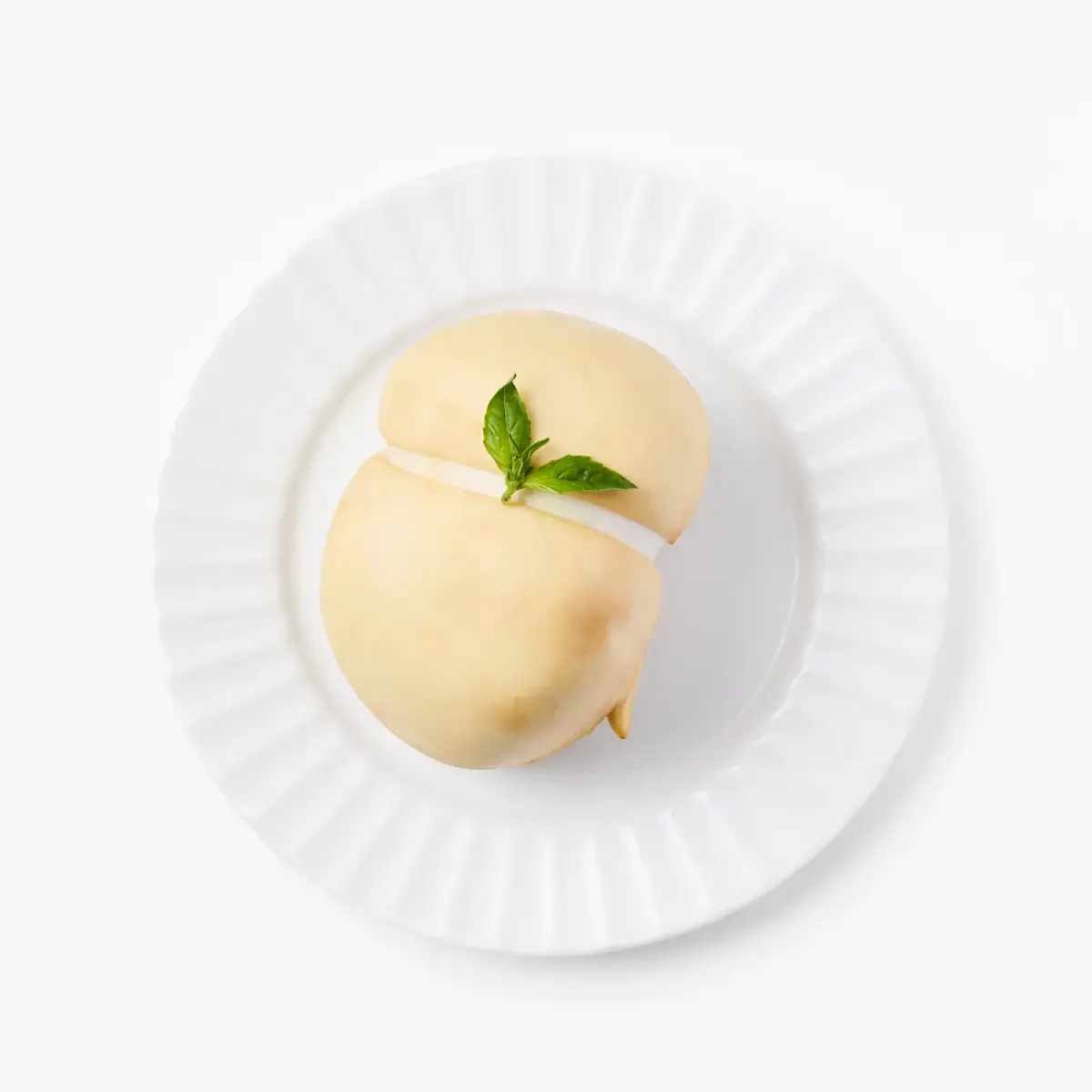 La Delizia Latticini smoked scamorza ball with golden rind and fresh basil on a white fluted plate
