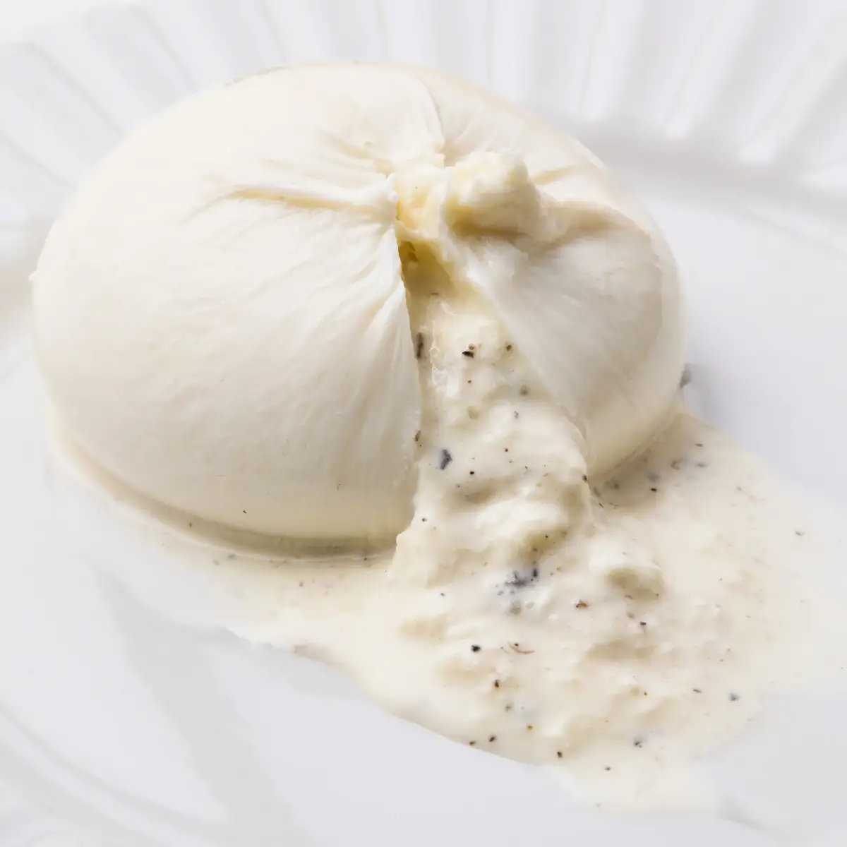 La Delizia Latticini truffle burrata cut open to show the creamy truffle-flecked stracciatella centre flowing onto the plate
