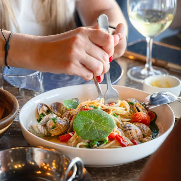Diner enjoying clam pasta, bright lifestyle photography suitable for Italian restaurant web design in Perth.