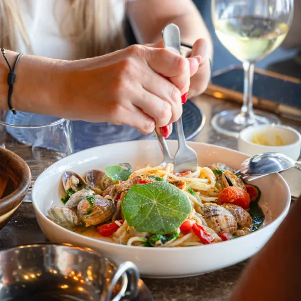 Diner enjoying clam pasta, bright lifestyle photography suitable for Italian restaurant web design in Perth.