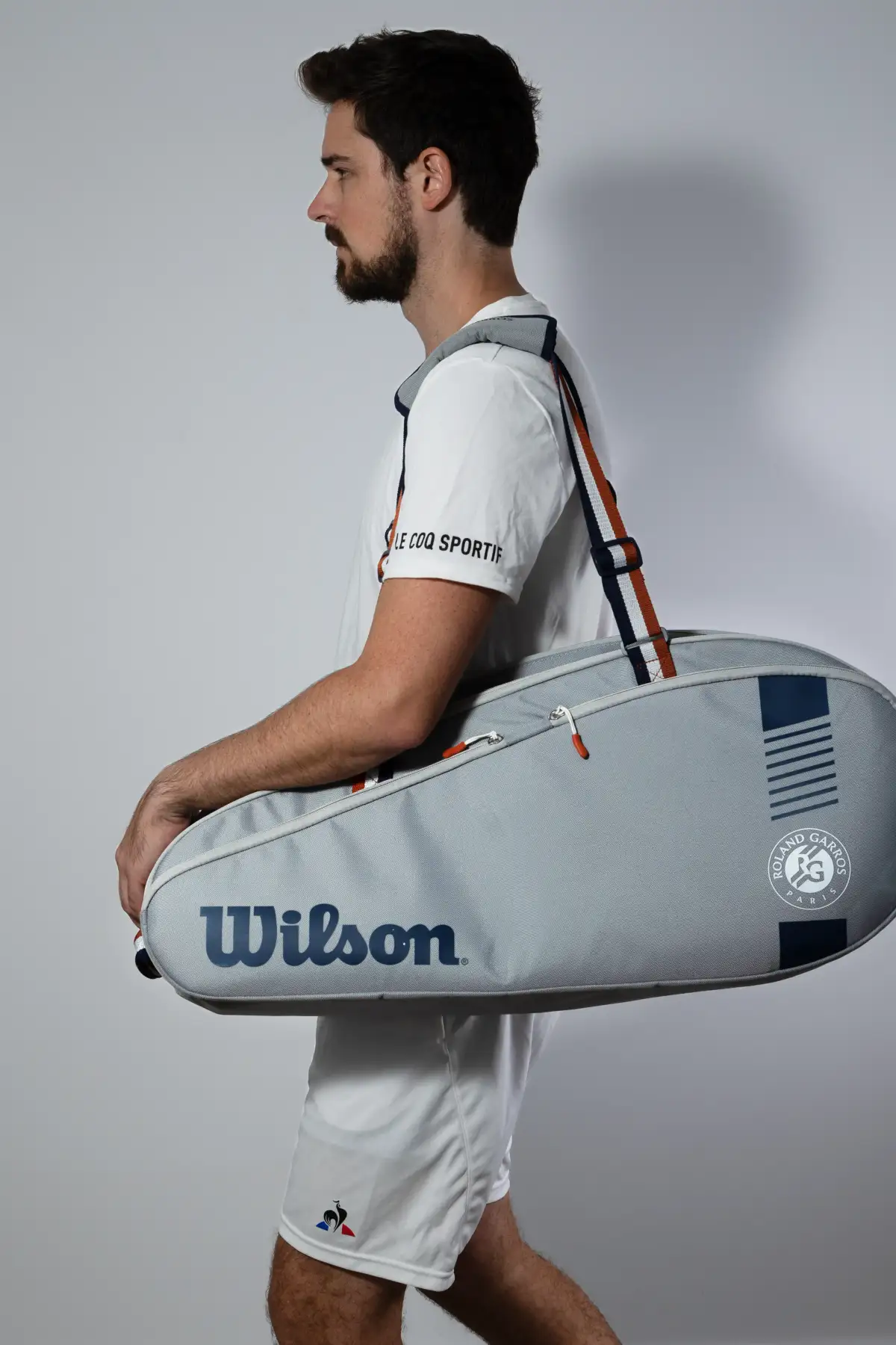 Model carrying a tennis bag during an outdoor lifestyle product session.